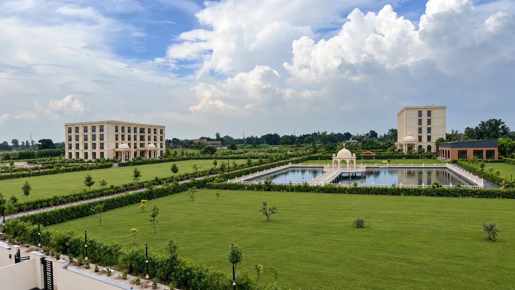 The open lawns by day under a big sky, with the pond and its mandap, the hotel and the Banquet Hall beyond