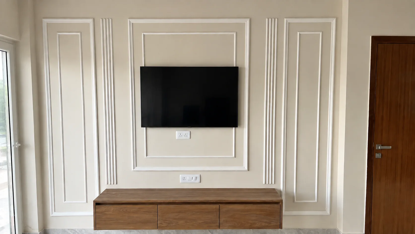 A villa's living room: a panelled cream wall with a television above a low wooden console